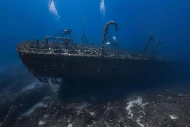 Deux plongeurs explorent l'épave d'un bateau coulé en mer