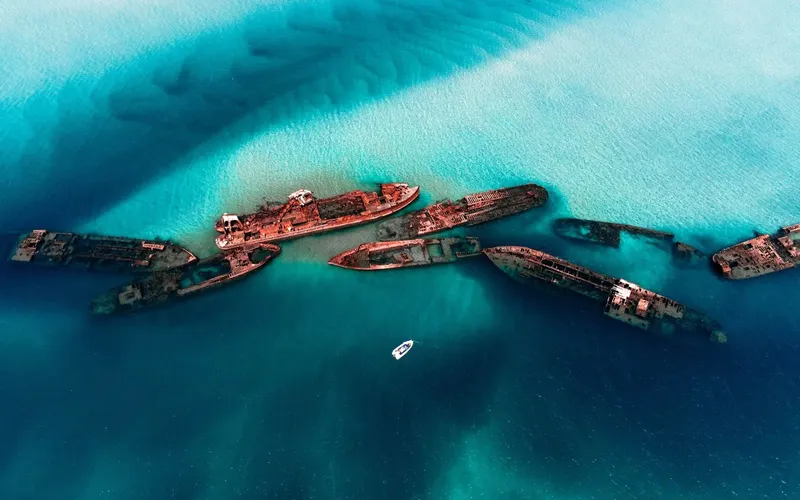 Épaves de navires rouillés reposant sur un fond marin turquoise clair