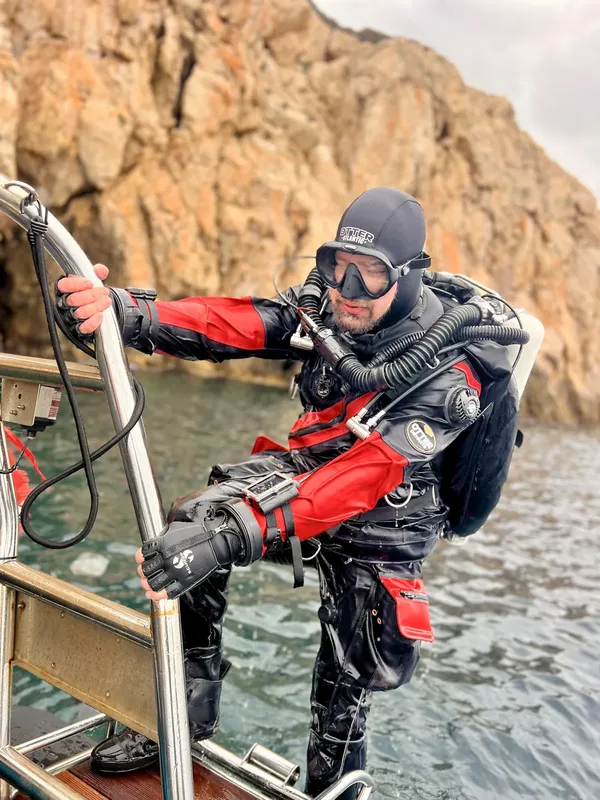 Plongeur en combinaison rouge se préparant à entrer dans l'eau