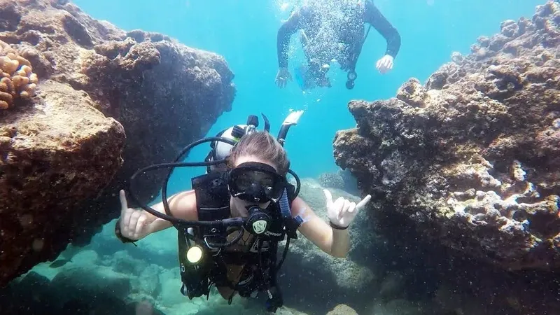 Deux plongeurs souriants font des signes de la main sous l'eau