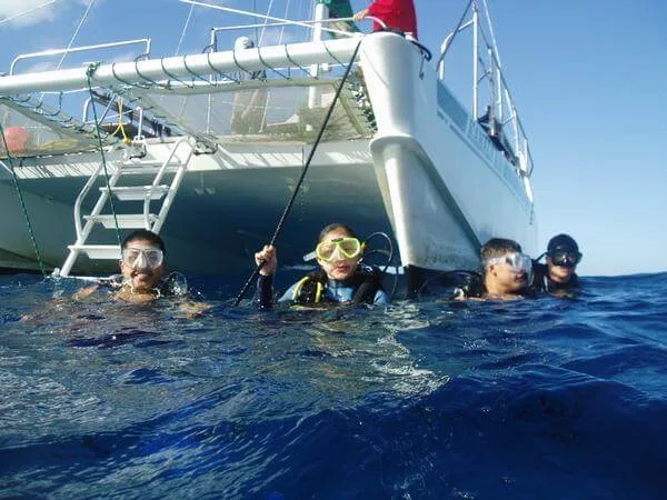 Plongeurs souriants émergent à proximité d'un catamaran en mer