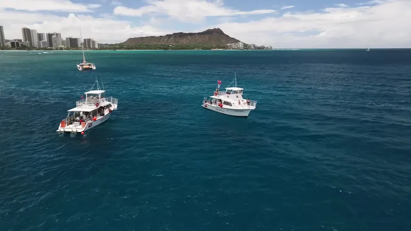 Trois bateaux de plongée naviguent sur une mer turquoise ensoleillée