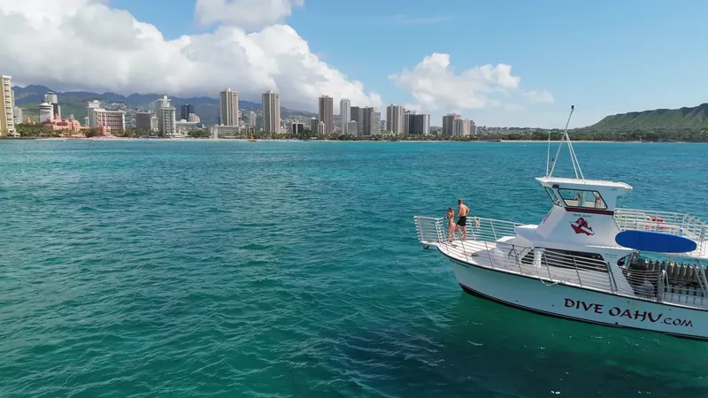 Bateau de plongée en mer avec des personnes à bord et ville en arrière-plan