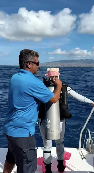 Un moniteur aide une plongeuse à attacher sa bouteille sur le bateau