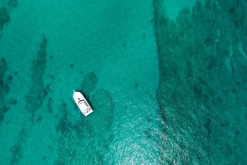 Vue aérienne d'un bateau de plaisance sur une eau turquoise et claire