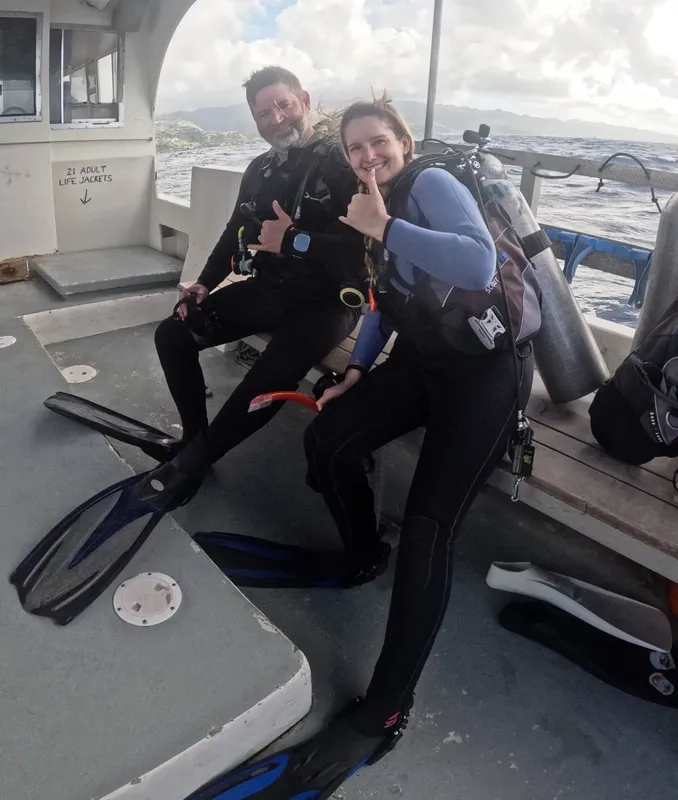 Deux plongeurs souriants sur un bateau, équipés pour une sortie
