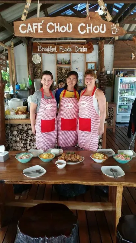 Trois femmes souriantes derrière un comptoir de café avec nourriture
