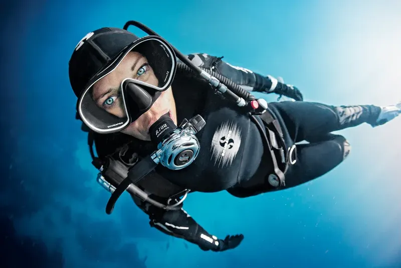 Plongeuse en combinaison noire nageant dans une eau bleue claire
