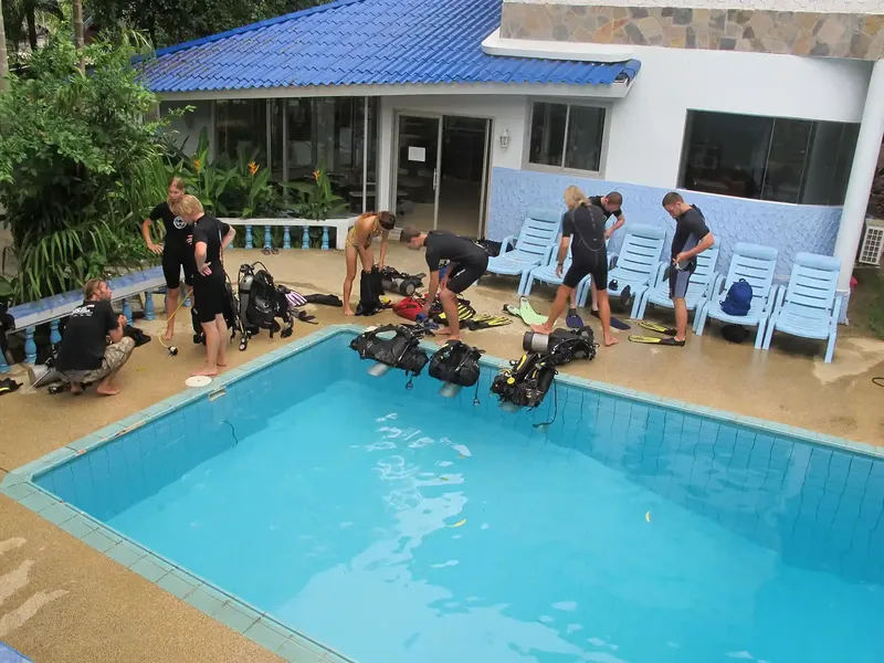 Groupe de plongeurs équipés près d'une piscine devant un bâtiment