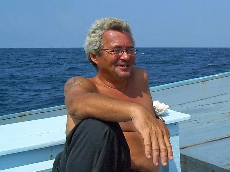 Homme souriant assis sur un bateau en mer, regardant l'horizon