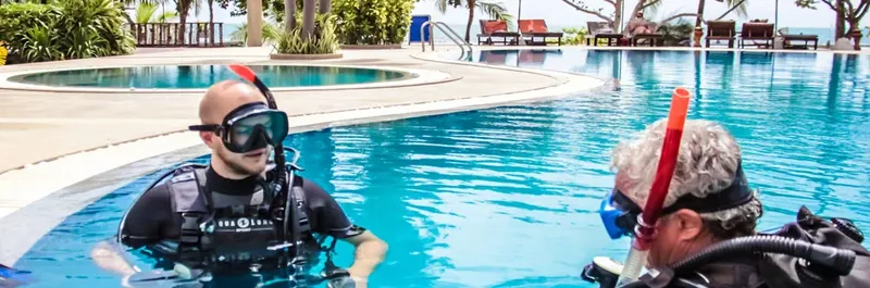 Deux plongeurs en formation dans une piscine, équipement complet visible