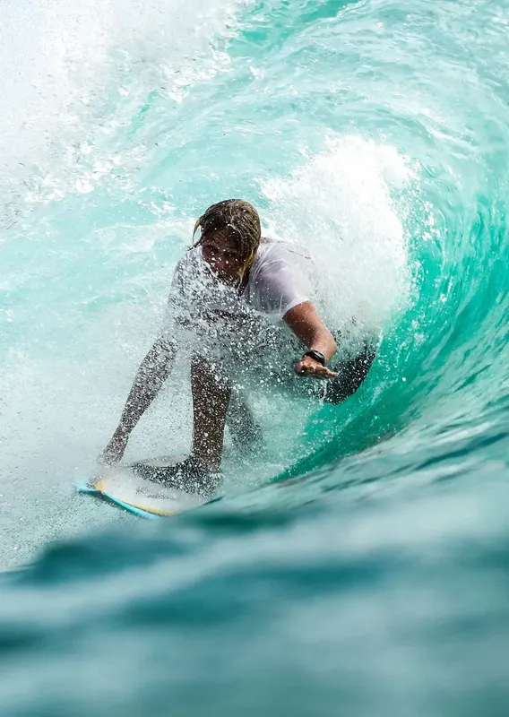 Surfeur dans une vague turquoise, action sportive, eau claire, mouvement