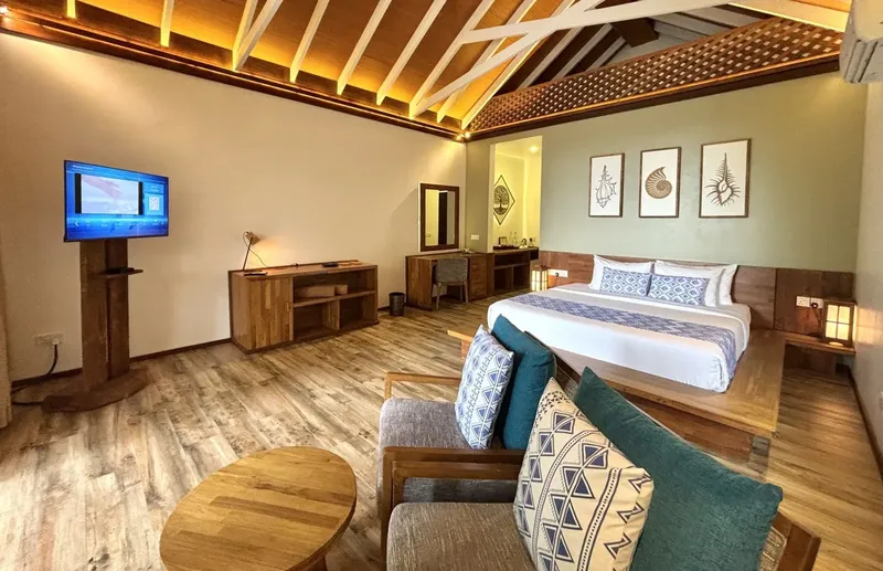 Chambre d'hôtel moderne avec lit, canapé, télévision et décoration marine