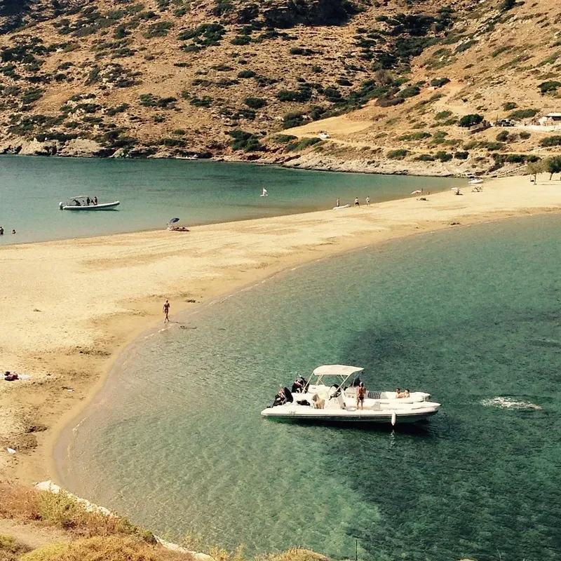 Plage de sable, mer turquoise, quelques personnes et un bateau à moteur