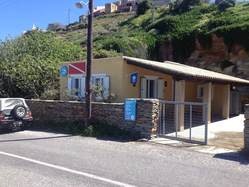 Façade d'un bâtiment jaune avec des logos de plongée et un parking