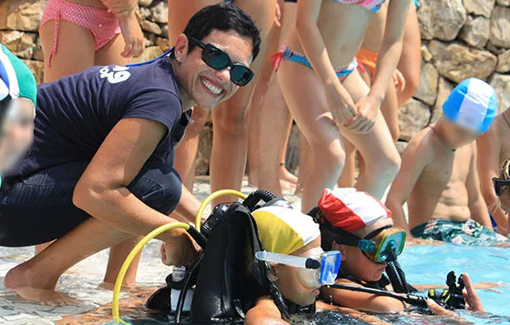 Instructrice aide un jeune plongeur à mettre son équipement piscine
