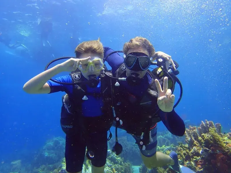 Deux plongeurs souriants font un signe de la main sous l'eau