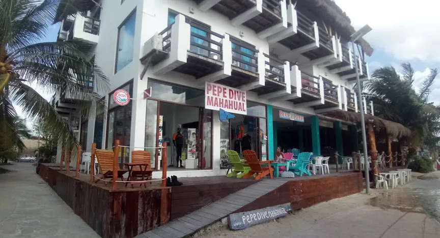 Façade d'un centre de plongée avec terrasse, chaises et équipements visibles