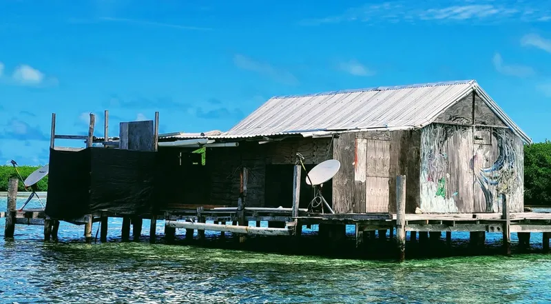 Cabane en bois sur pilotis au-dessus d'une eau turquoise claire