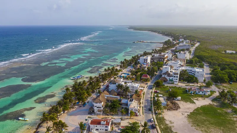 Vue aérienne d'une côte turquoise avec bâtiments et végétation luxuriante