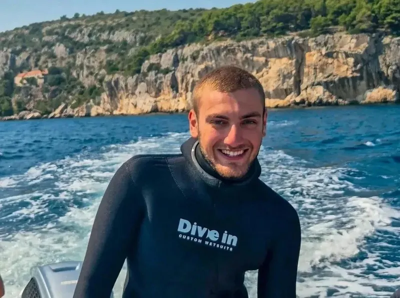 Jeune homme souriant portant une combinaison de plongée sur un bateau