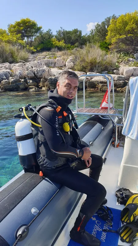 Plongeur équipé assis dans un bateau pneumatique près du rivage