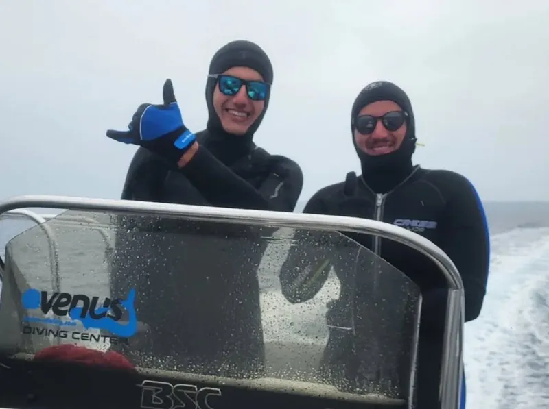 Deux plongeurs souriants en combinaison sur un bateau en mer