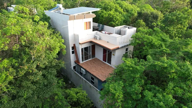 Bâtiment blanc moderne avec terrasses et végétation luxuriante environnante