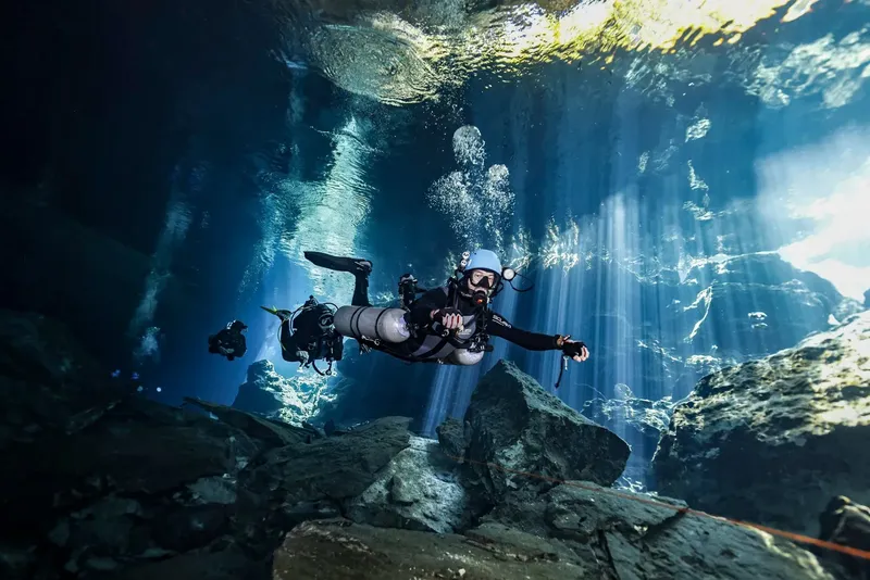 Plongeur explore une grotte sous-marine avec des rayons de lumière