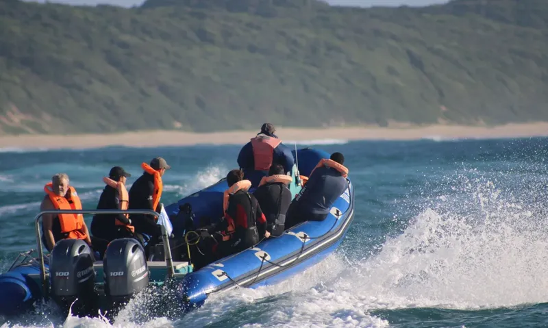 Groupe de personnes en gilet de sauvetage à bord d'un semi-rigide en mer