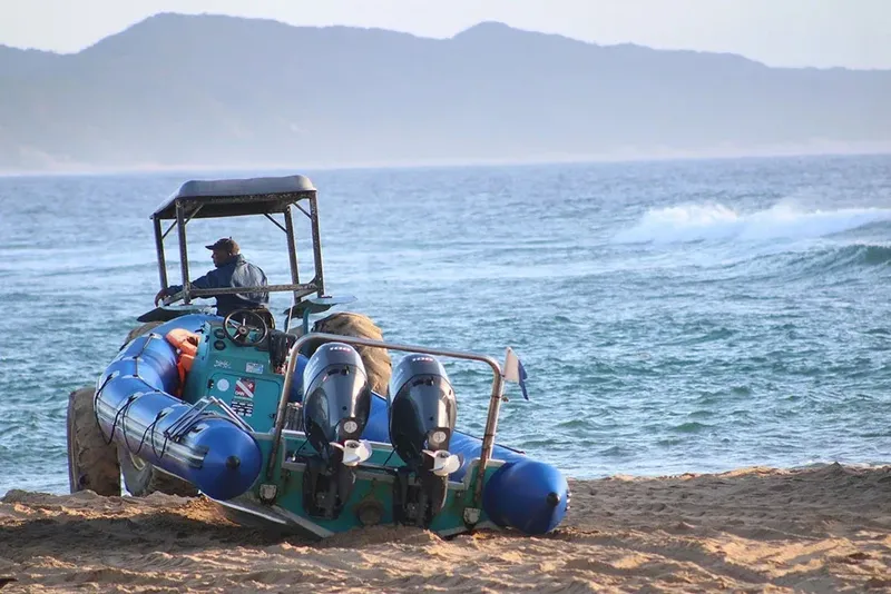 Bateau semi-rigide sur une plage de sable avec un pilote et passagers