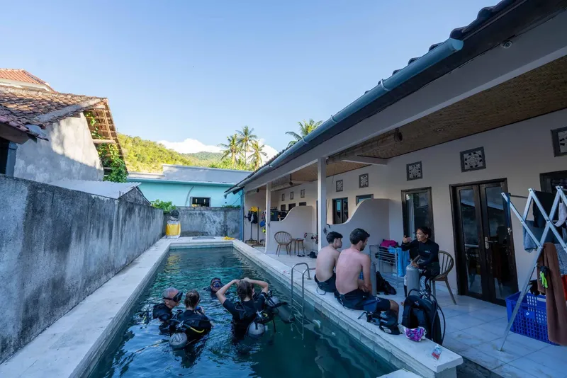 Plongée : groupe de personnes équipées près d'une piscine et d'un bâtiment
