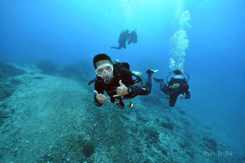 Trois plongeurs souriants en pleine immersion, geste de validation
