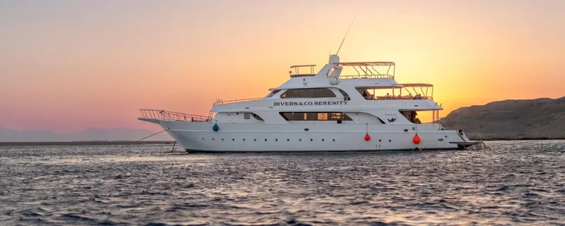 Grand bateau de plongée blanc amarré au coucher du soleil en mer
