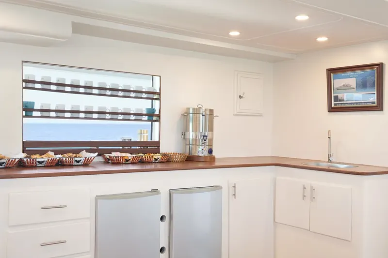 Interieur lumineux avec comptoir, cafetiere, refrigerateurs et vue mer