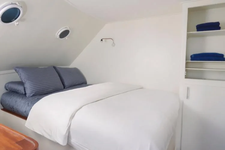 Intérieur d'une cabine de bateau avec lit, oreillers et rangements