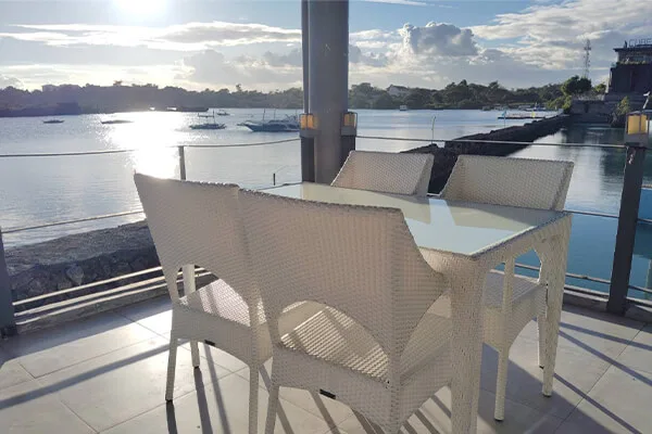 Terrasse avec mobilier blanc, vue sur la mer et bateaux