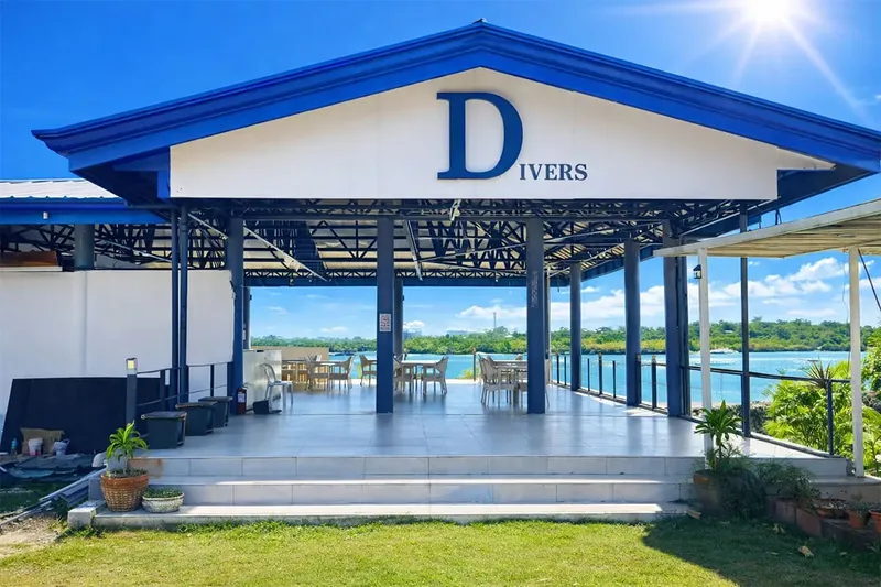 Façade d'un centre de plongée avec une vue sur la mer et la végétation