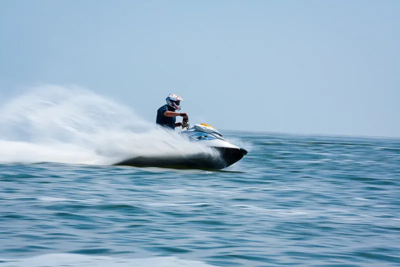 Pilote de jet ski en pleine vitesse sur une mer bleue