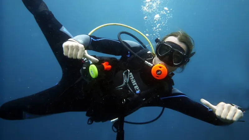 Plongeuse souriante avec signe 'ok' sous l'eau, combinaison noire