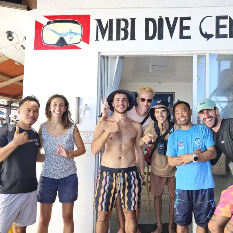Groupe de personnes souriantes devant l'entrée d'un centre de plongée