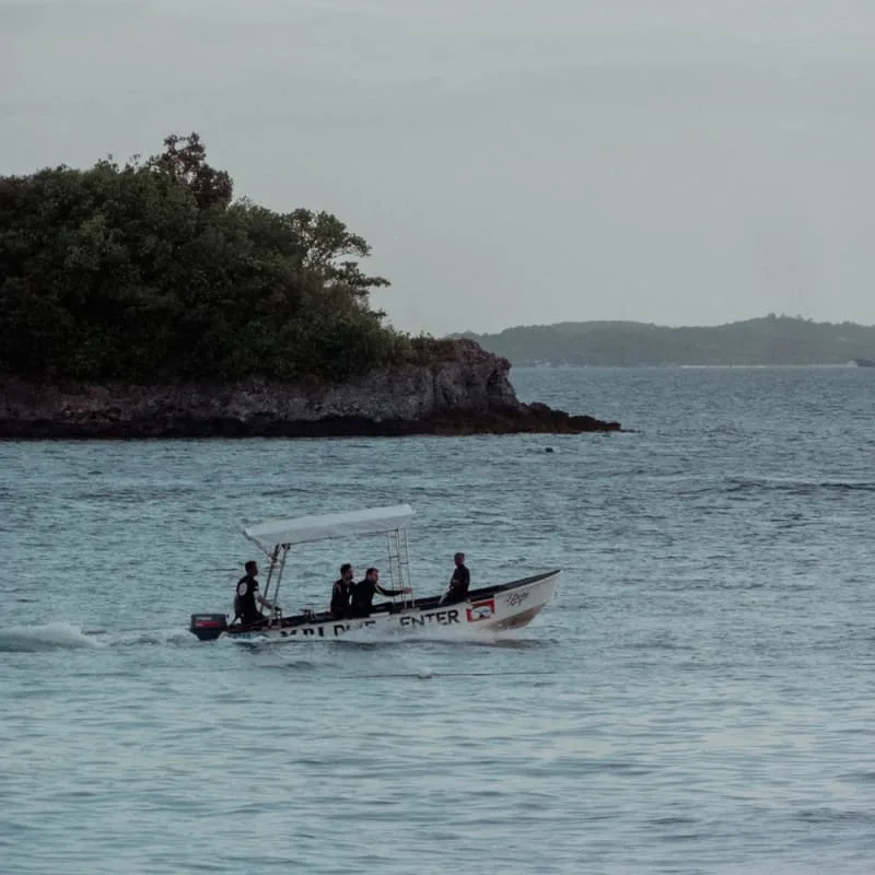 Trois personnes à bord d'un petit bateau blanc sur l'eau