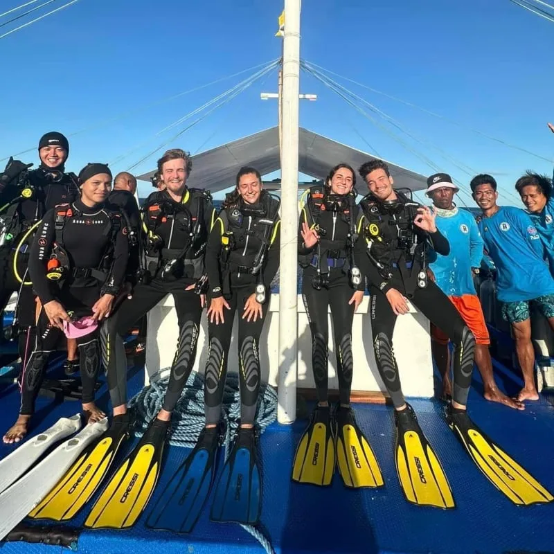 Groupe de plongeurs souriants équipés sur le pont d'un bateau