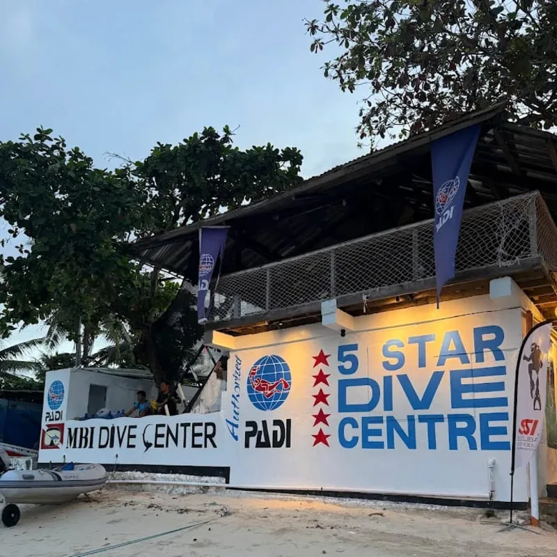 Façade d'un centre de plongée avec bateau, personnes et drapeaux PADI
