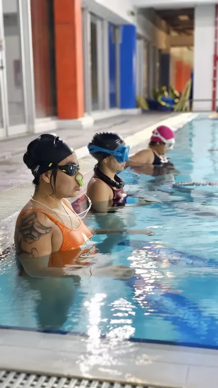Trois femmes en maillot de bain et bonnet de bain dans une piscine