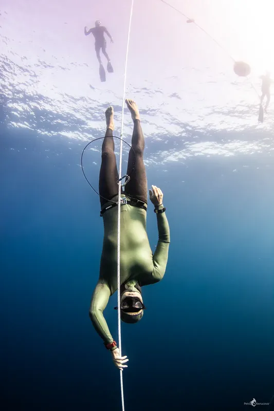 Apnée : plongeur descendant le long d'un câble dans l'eau bleue