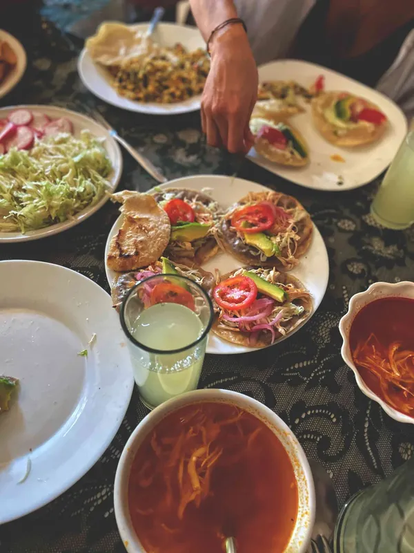 Table garnie de plats mexicains, main ajoutant un ingrédient