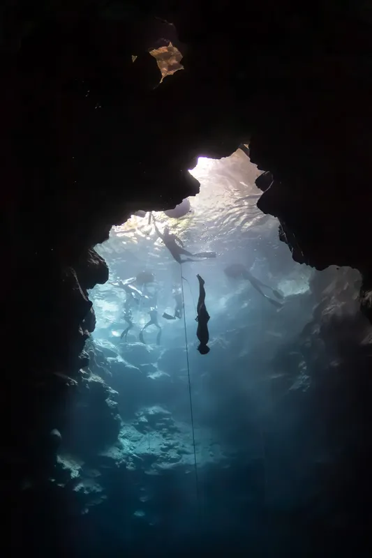 Plongeurs explorant une grotte sous-marine, lumière filtrant à la surface