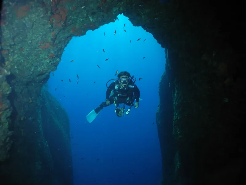 Plongeur explorant une grotte sous-marine avec une lumière bleue intense