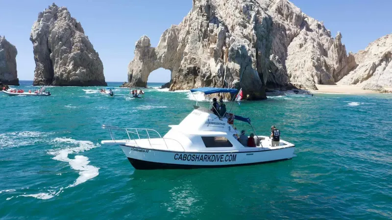 Bateau de plongée en mer avec des personnes à bord et paysage rocheux